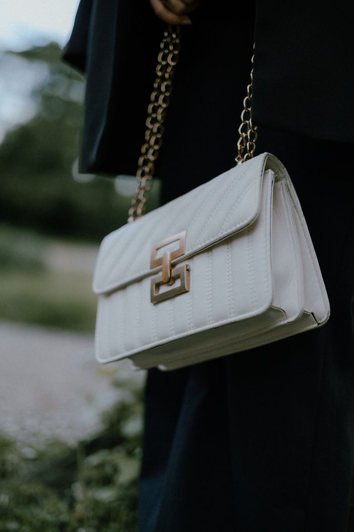 Stylish white handbag with gold chain details, perfect for any occasion.